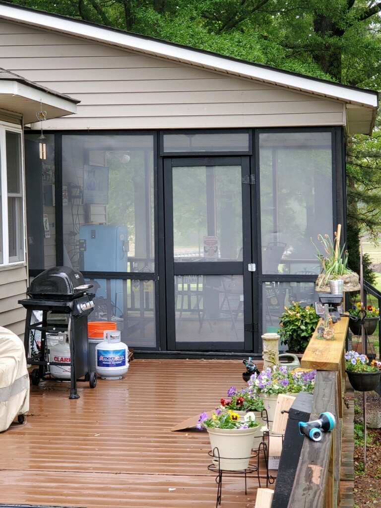 exterior image of enclosed patio with wood deck and barbeque