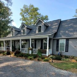 Front of home with windows and roofing with patio and white railings