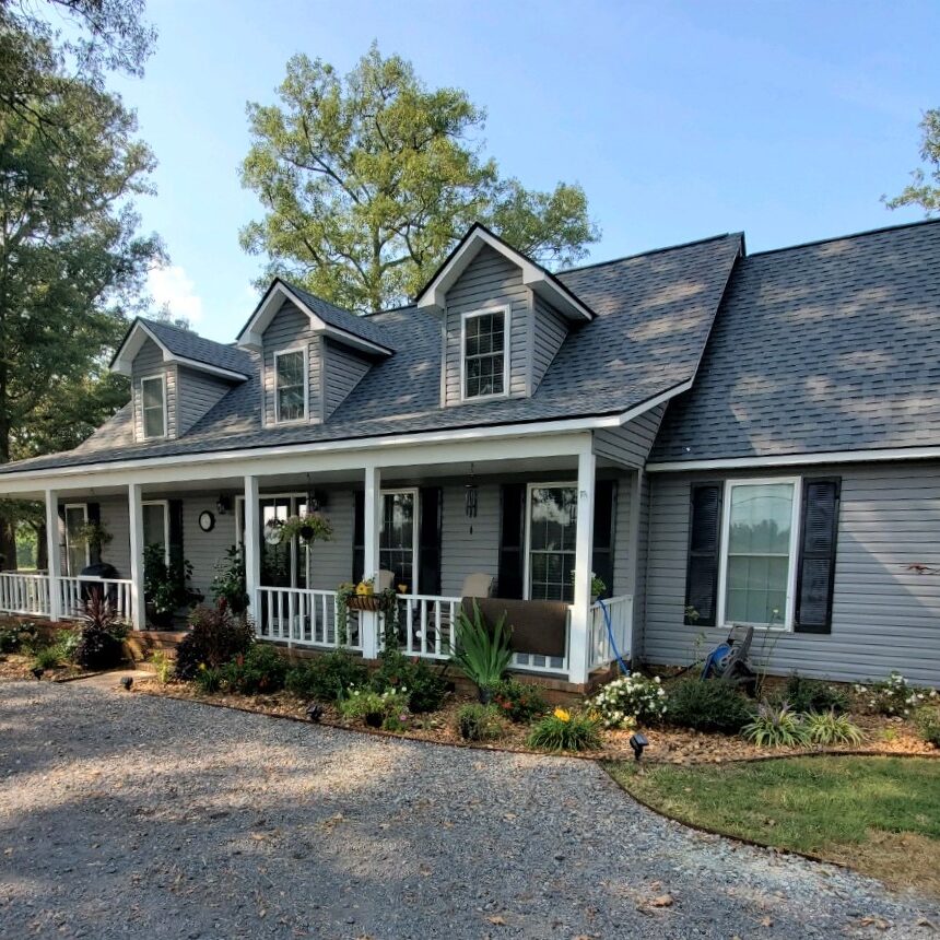 Front of home with windows and roofing with patio and white railings