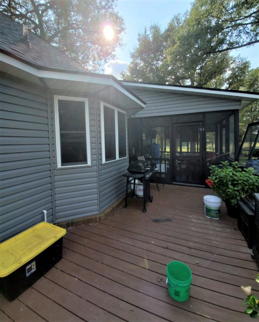 siding on home with exterior of enclosed patio visible with wood desk