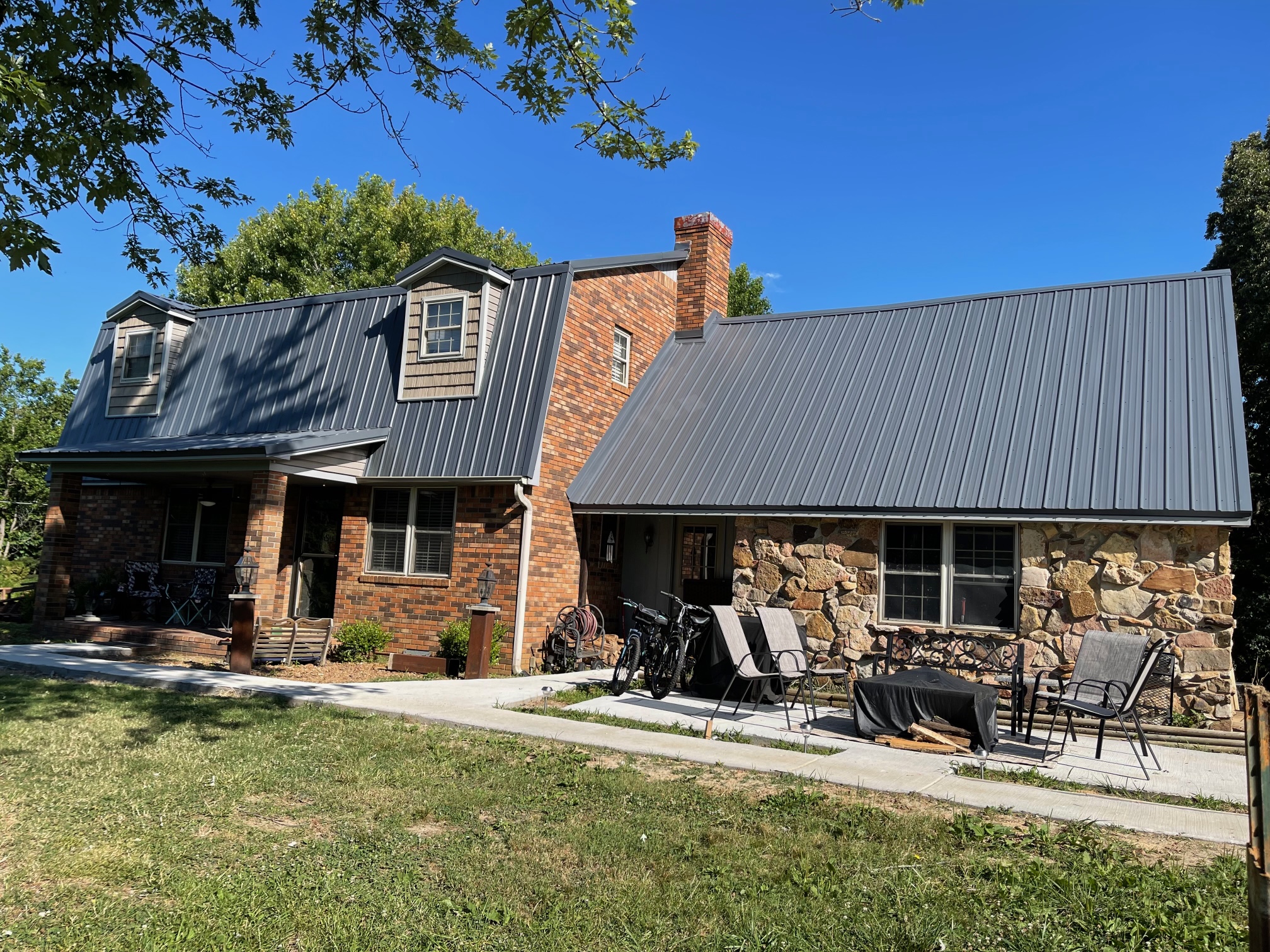 brick home with metal roofing and patio in front with furniture